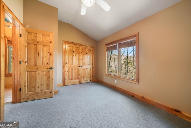 unfurnished bedroom featuring a ceiling fan, baseboards, vaulted ceiling, and carpet flooring