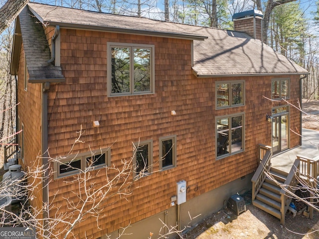 view of side of property featuring a chimney and roof with shingles