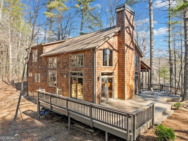 rear view of house with a chimney and a wooden deck