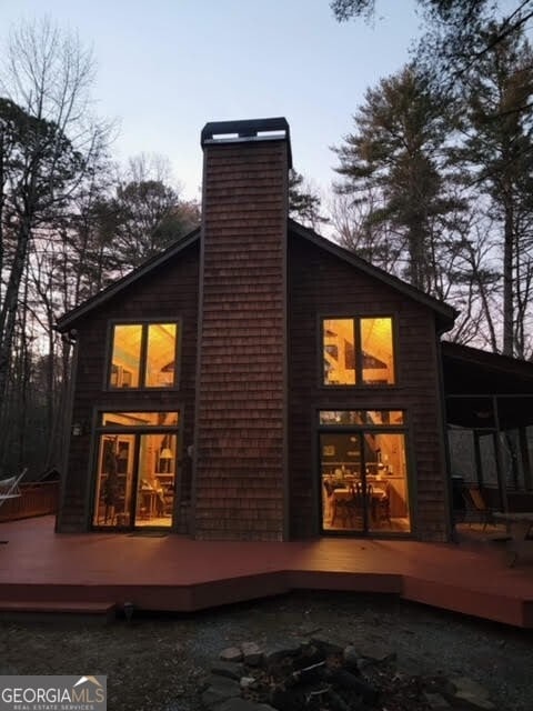 back of property featuring a sunroom, a chimney, and a deck