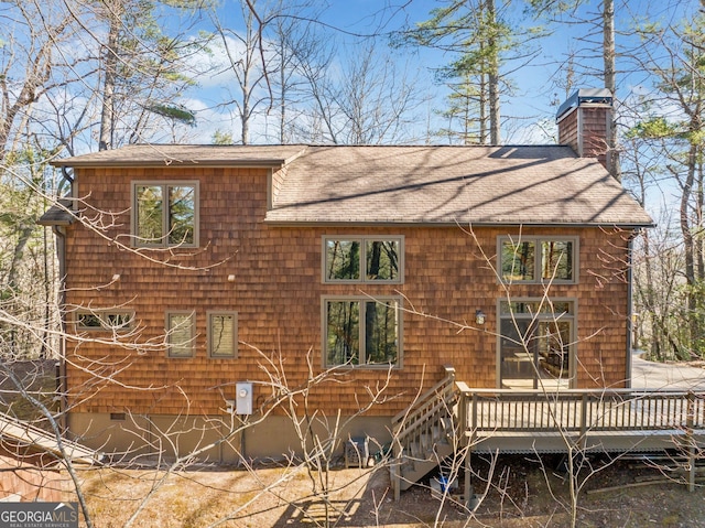 rear view of property with a deck, a shingled roof, and a chimney