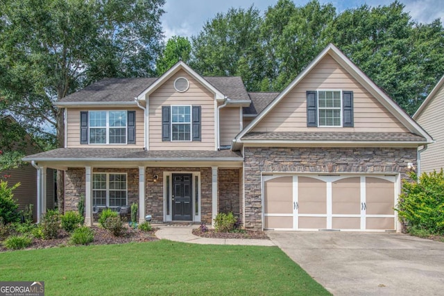 view of front of house featuring driveway, a garage, stone siding, covered porch, and a front lawn