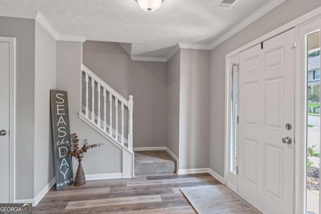 entrance foyer with crown molding, stairway, a textured ceiling, wood finished floors, and baseboards