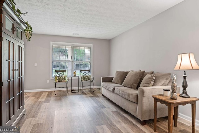 living room with a textured ceiling, wood finished floors, and baseboards
