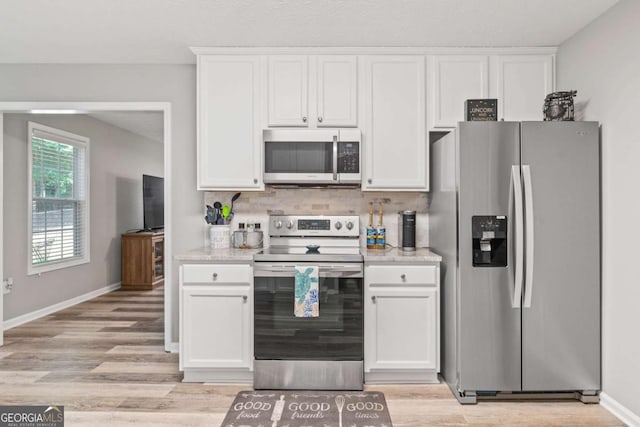 kitchen featuring stainless steel appliances, white cabinets, backsplash, and light wood finished floors