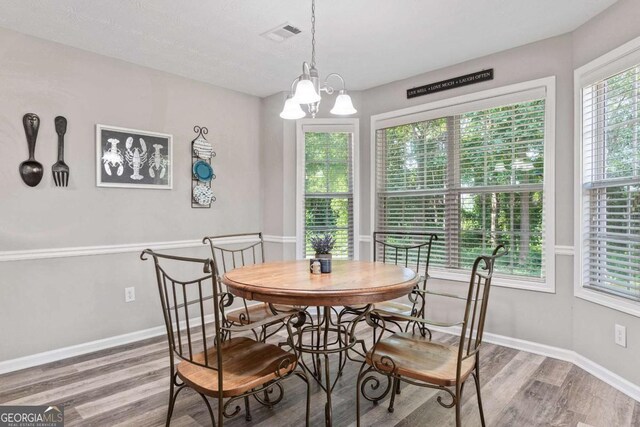 dining space featuring a chandelier, wood finished floors, visible vents, and baseboards