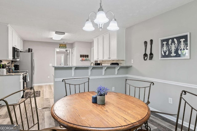 dining area with light wood-style flooring, a chandelier, and baseboards