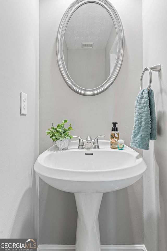 bathroom featuring baseboards, visible vents, and a sink