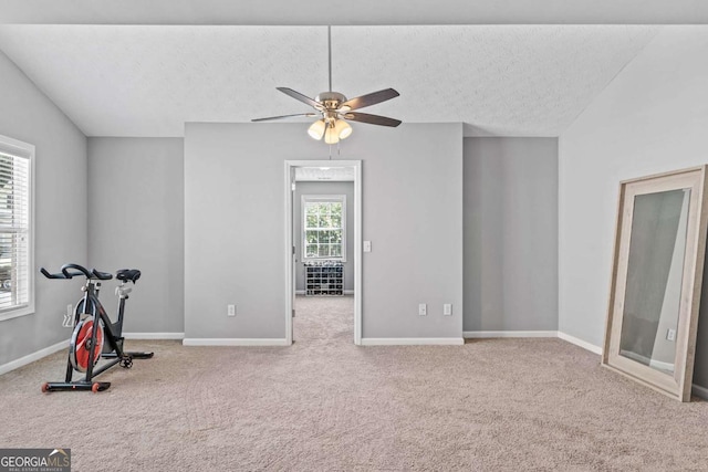 workout area with baseboards, a ceiling fan, lofted ceiling, carpet, and a textured ceiling