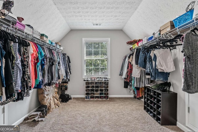 walk in closet featuring carpet, visible vents, and vaulted ceiling