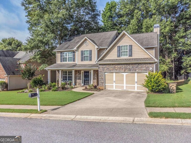 view of front of property featuring a chimney, a front yard, a garage, stone siding, and driveway