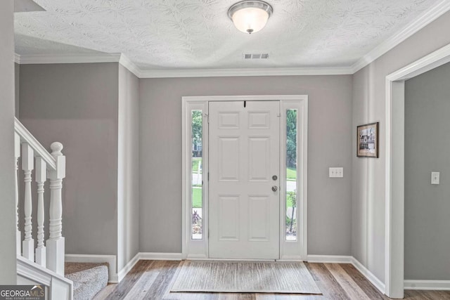 foyer entrance with visible vents, plenty of natural light, and wood finished floors