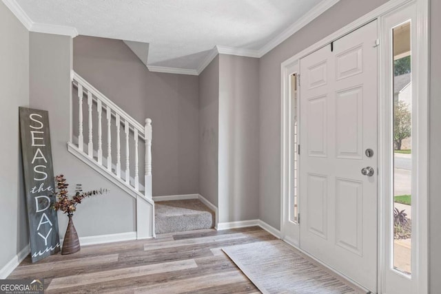 entrance foyer featuring crown molding, stairway, baseboards, and wood finished floors