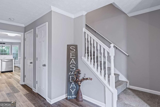 stairway with a textured ceiling, ornamental molding, wood finished floors, and baseboards