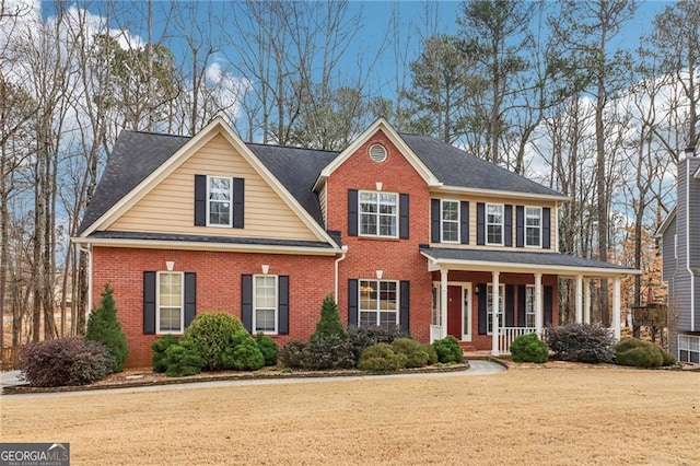 view of front of property featuring a porch, a front yard, and brick siding