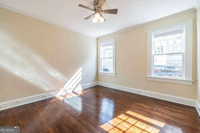 spare room featuring baseboards, ornamental molding, dark wood-type flooring, and a wealth of natural light