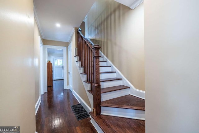 staircase featuring ornamental molding, visible vents, baseboards, and wood finished floors