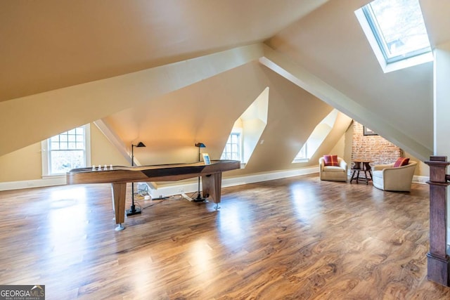 additional living space with vaulted ceiling with skylight, baseboards, and wood finished floors