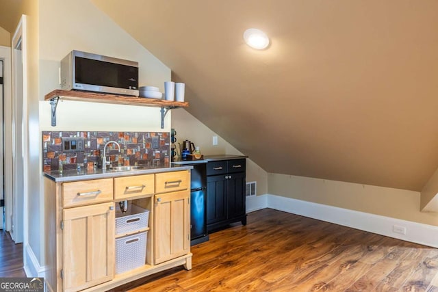 bar featuring visible vents, lofted ceiling, stainless steel microwave, dark wood-type flooring, and a sink