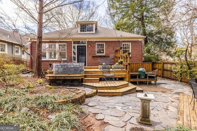 back of house featuring a deck, fence private yard, brick siding, a shingled roof, and a patio area