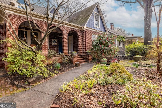 view of front of home featuring a shingled roof and brick siding