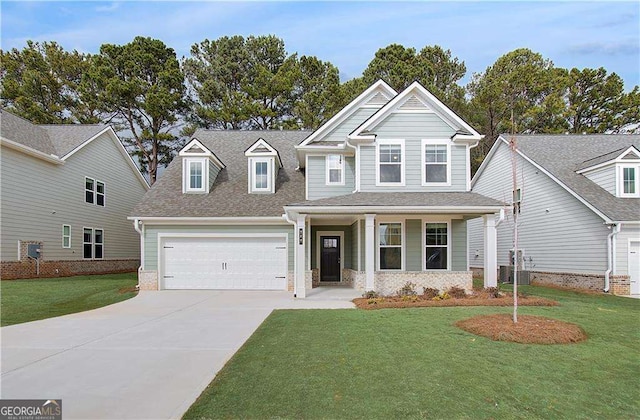 view of front facade featuring covered porch, a garage, driveway, roof with shingles, and a front yard