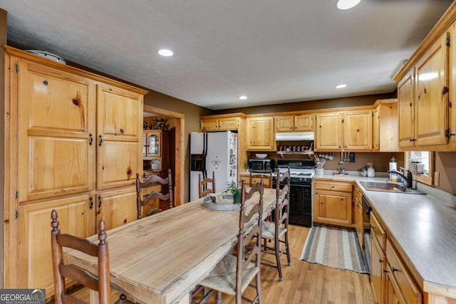 kitchen featuring range with gas stovetop, light countertops, stainless steel microwave, fridge with ice dispenser, and a sink