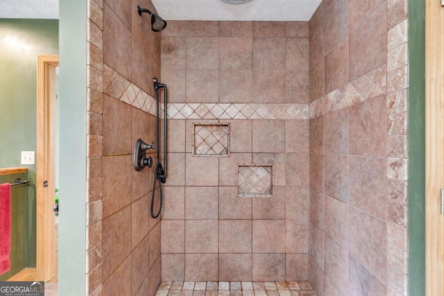 bathroom with a textured ceiling and a tile shower