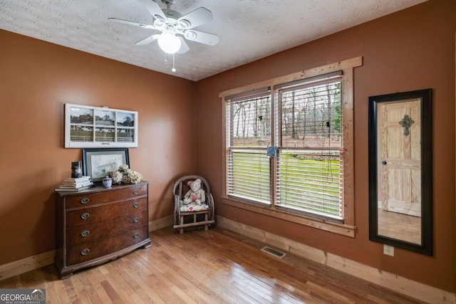 living area featuring light wood-style floors, visible vents, plenty of natural light, and baseboards