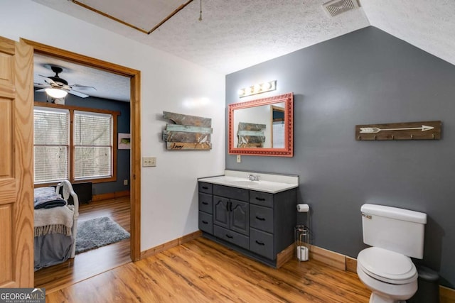 ensuite bathroom with a textured ceiling, toilet, wood finished floors, vanity, and visible vents