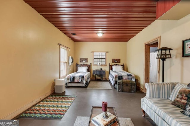 bedroom featuring wooden ceiling, finished concrete flooring, and baseboards