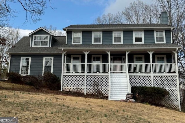 view of front of house featuring roof with shingles, a porch, and a front yard