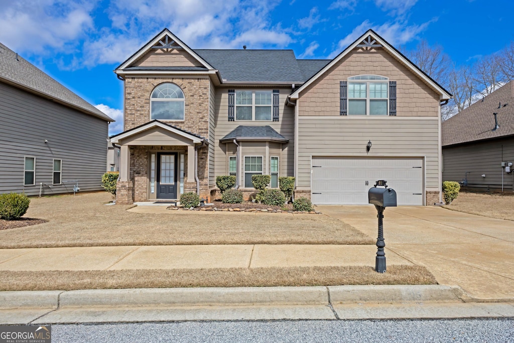 craftsman-style home featuring a garage, concrete driveway, brick siding, and roof with shingles