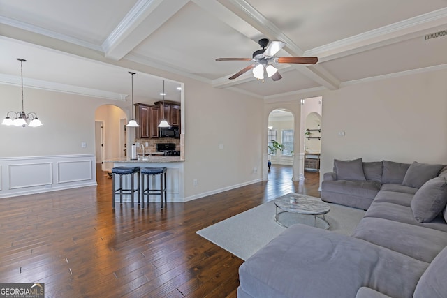 living area with visible vents, arched walkways, dark wood finished floors, and beamed ceiling