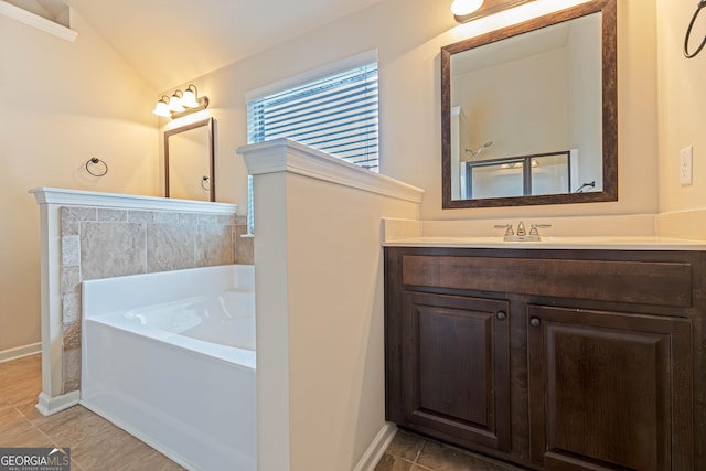 bathroom with baseboards, lofted ceiling, tile patterned floors, a garden tub, and vanity