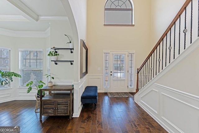 entryway with stairs, dark wood finished floors, beamed ceiling, and a decorative wall