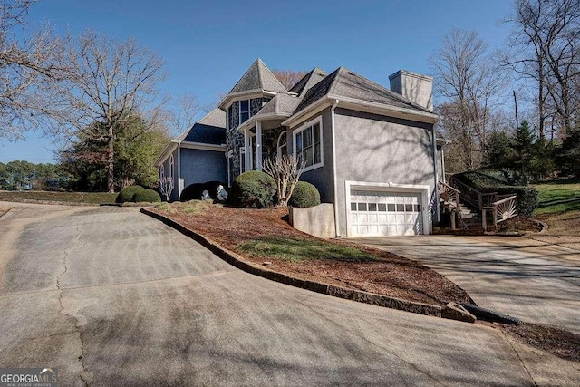 view of front of house featuring an attached garage, a chimney, concrete driveway, and stucco siding