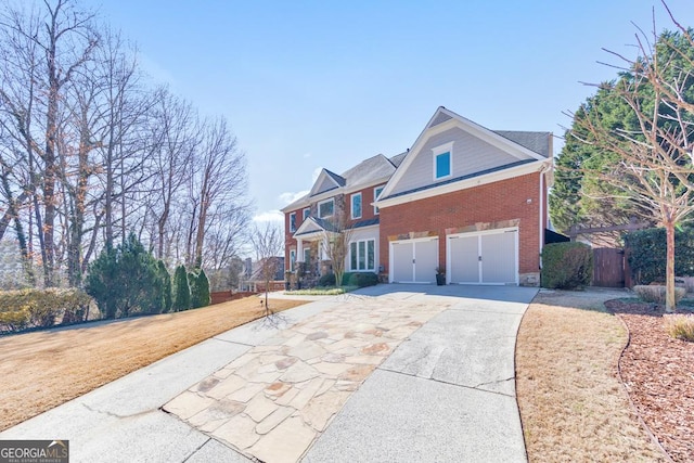 view of front facade with a garage, brick siding, driveway, and fence