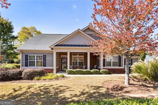 craftsman-style home featuring roof with shingles, a front lawn, and brick siding