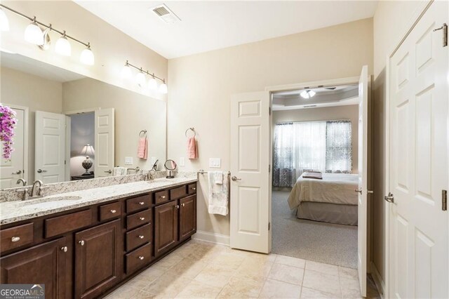 full bathroom with ensuite bathroom, double vanity, a sink, and tile patterned floors