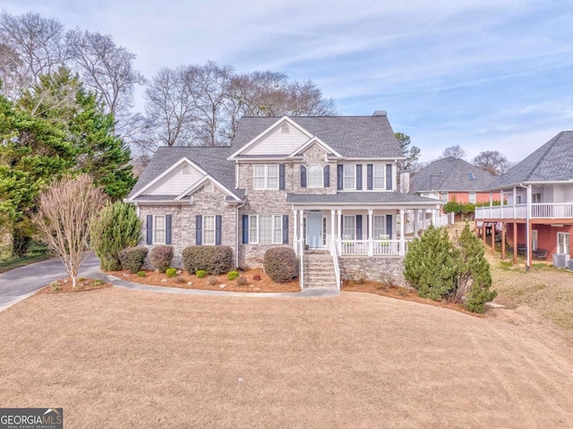 view of front of house with covered porch, stone siding, and driveway