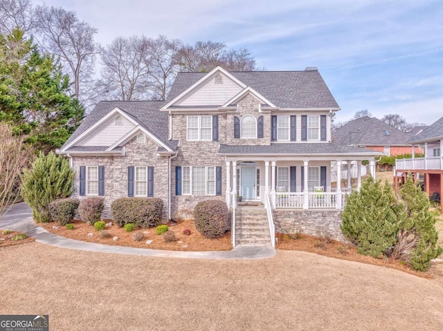 view of front of house featuring a porch, stone siding, and roof with shingles