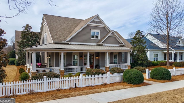 view of front of home featuring covered porch, metal roof, a standing seam roof, and a fenced front yard