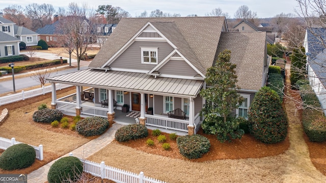 view of front of home featuring a shingled roof, covered porch, a standing seam roof, metal roof, and fence