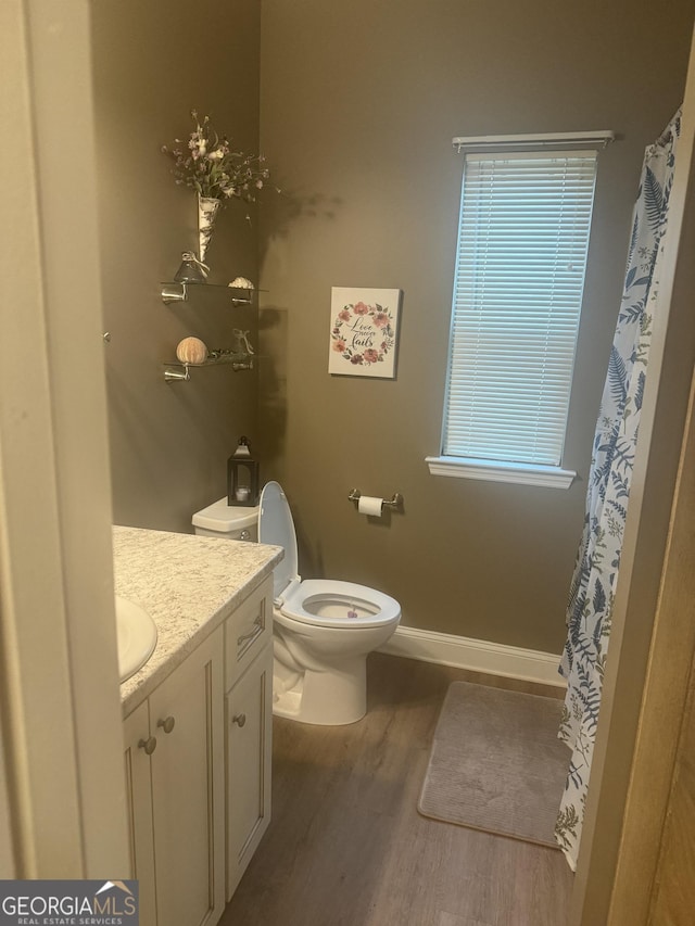 bathroom with baseboards, vanity, toilet, and wood finished floors