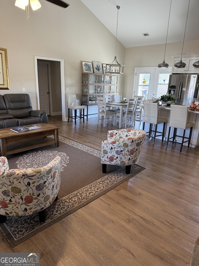 living room featuring dark wood-style floors, high vaulted ceiling, ceiling fan, and visible vents