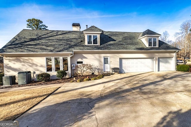 view of front of house featuring driveway, a garage, a shingled roof, cooling unit, and stucco siding