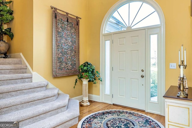 entryway with stairway, wood finished floors, and baseboards