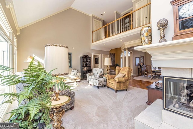 living room featuring wood finished floors, crown molding, ornate columns, high vaulted ceiling, and a multi sided fireplace