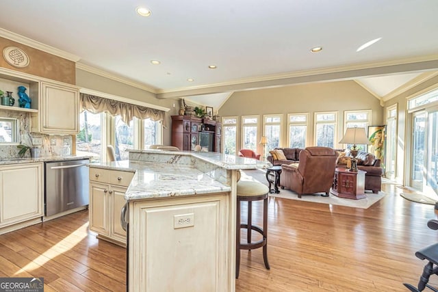 kitchen featuring light wood finished floors, dishwasher, lofted ceiling, a breakfast bar area, and cream cabinetry